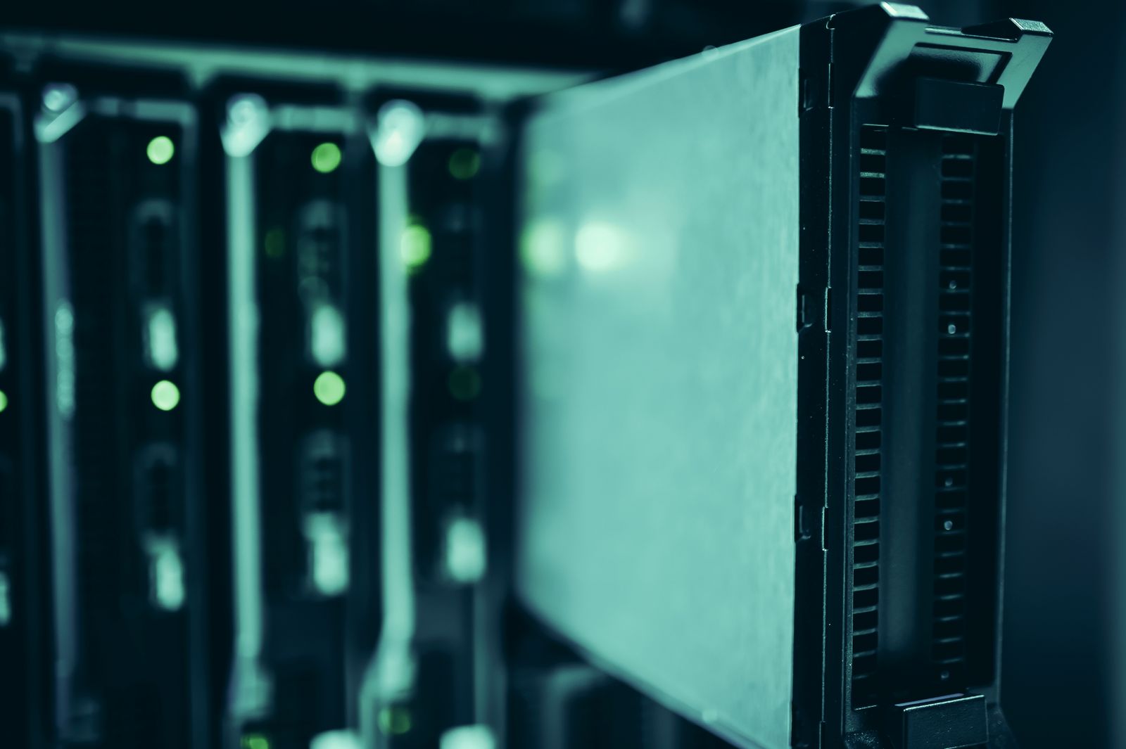 Close-up of a server drive sled being pulled from a rack in a blue-lit data center