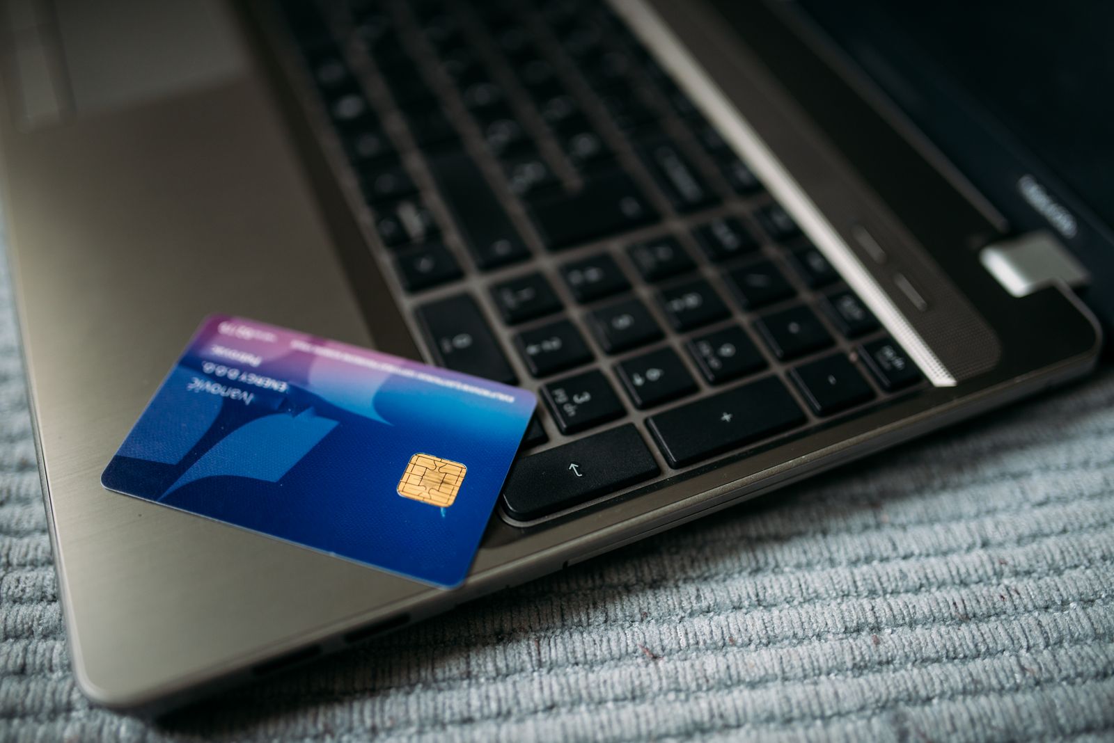 A blue chip card lying on the keyboard of an open laptop